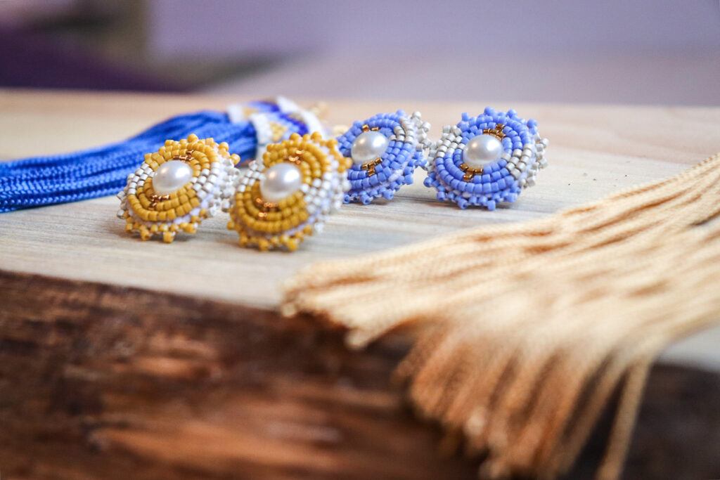 two pairs of beaded studs, one yellow and one blue, with pearls in their centres