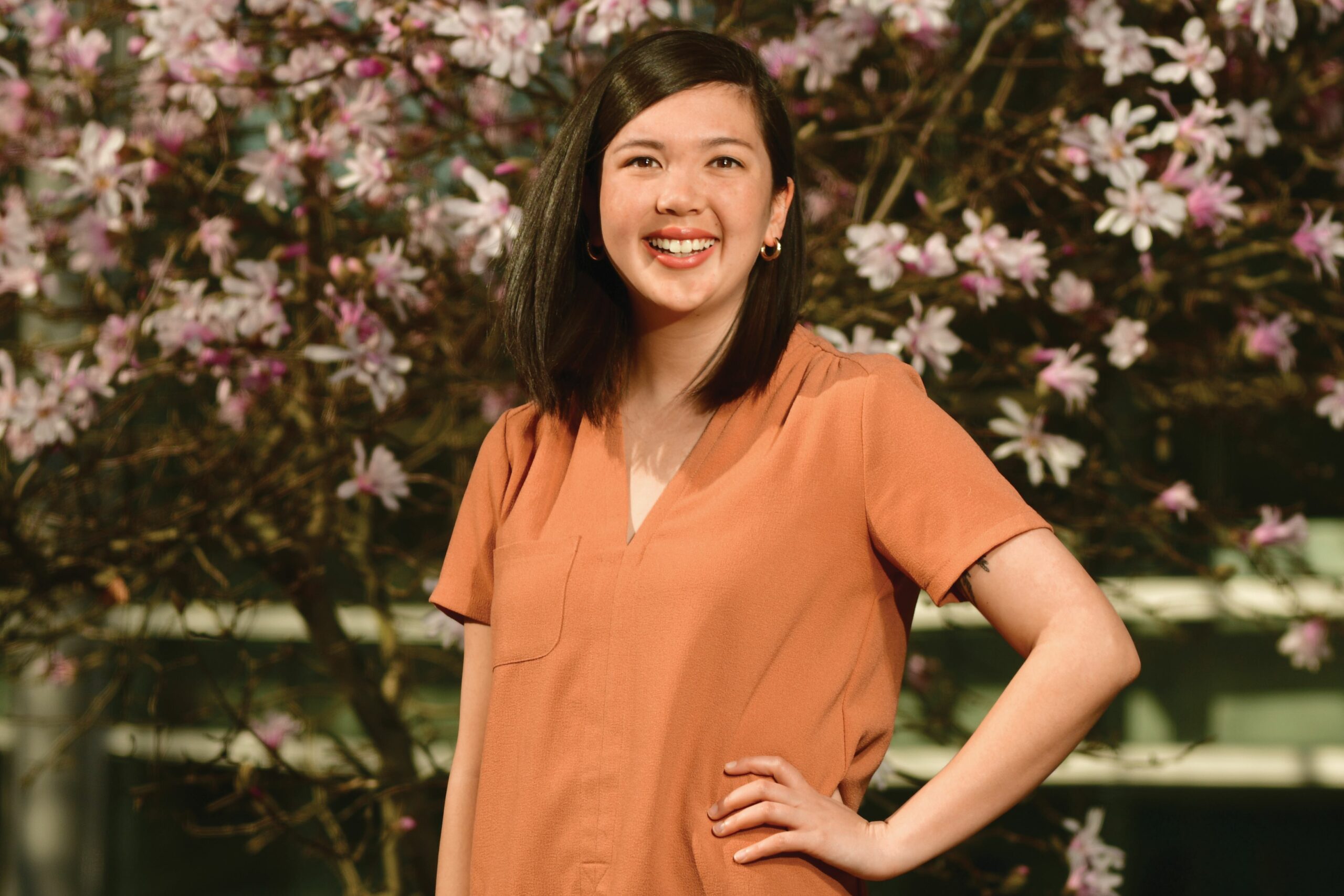author photo of Emily Chan, smiling and standing in front of cherry blossoms.