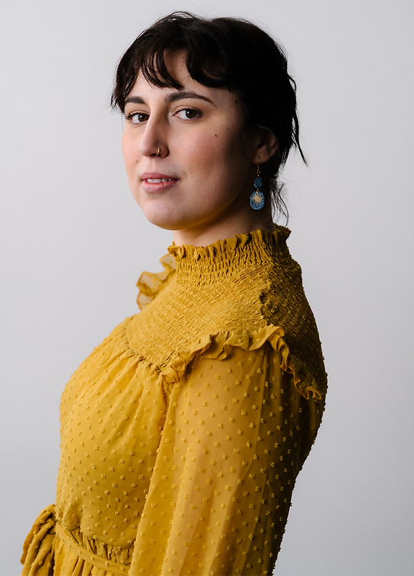 SydneyBrooman_HR_sarahbodri2021-8_edited photo of Sydney Hegele standing sideways in a yellow top.